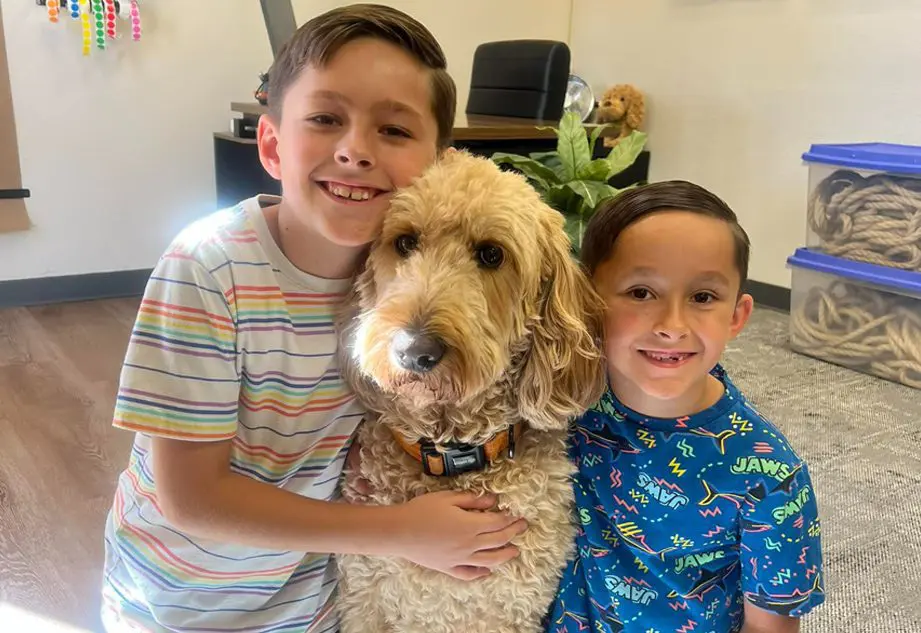 Two boys and a dog are posing for the camera.